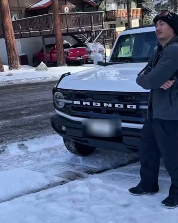 A snowbound mountain street beside a parked Bronco